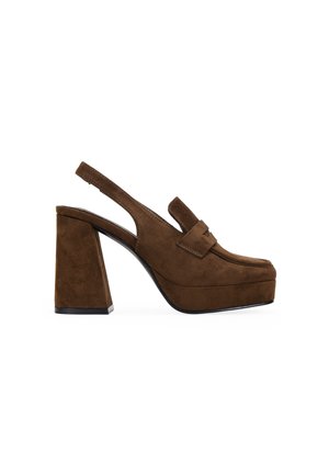 Zapato de plataforma con tira trasera para mujer en ante marrón, con tacón de bloque y parte superior estilo mocasín sobre fondo blanco.