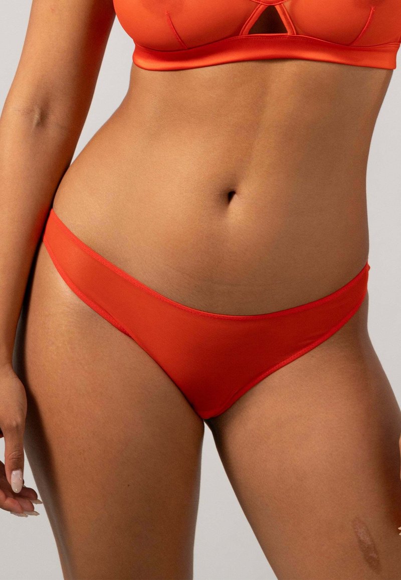 Slip bikini rossi con una texture liscia e raffinata, design a vita bassa e copertura minima, caratterizzati da un semplice elastico in vita.