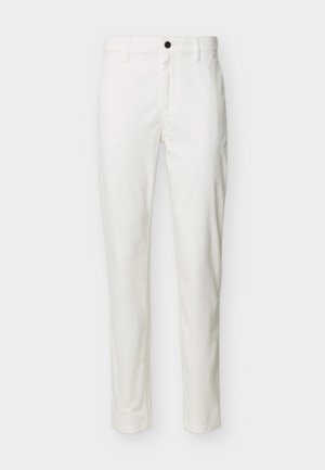 Białe spodnie o dopasowanym kroju z czarnym guzikiem, szlufkami na pasek i zapięciem na zamek z przodu, prezentowane na jednolitym tle.