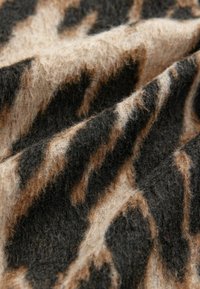 Sekana leopardi dengan tekstur lembut dan berbulu. Memiliki pola bergantian hitam dan cokelat muda, menampilkan desain bergelombang.