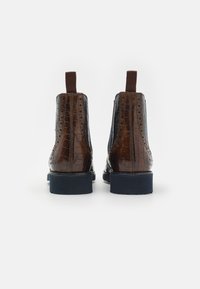 Botas de tornozelo em pele embossed de crocodilo marrom com solas de borracha azul-marinho, apresentando uma alça de puxar e detalhes de brogue na parte superior.