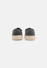Sneakers in suede grigio con punta rotonda e suola piatta in gomma beige. Presentano il marchio TOMS sul tallone e una finitura testurizzata.