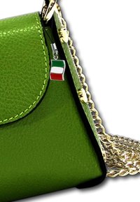 Groene leren handtas met een gestructureerde afwerking, gouden kettinghengsel en een metalen Italiaanse vlag charm die aan de sluiting is bevestigd.