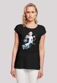 T-shirt noir à manches courtes présentant un graphique d'un personnage en robe blanche, entouré de flocons de neige et d'un fond givré.