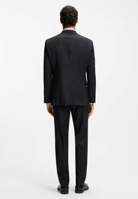 Czarny garnitur w delikatne prążki o dopasowanym kroju, z pojedynczym rozcięciem z tyłu, wykonany z dopasowanego materiału, z pasującymi spodniami.