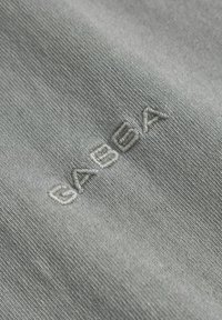 Textura de țesătură gri cu un model subtil în dungi. Logo-ul brodat "GABY" într-o nuanță mai deschisă de gri pe suprafață.