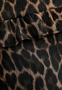 Tela de estampado de leopardo en negro y marrón con un detalle de volante texturizado, ligeramente translúcido y en capas.