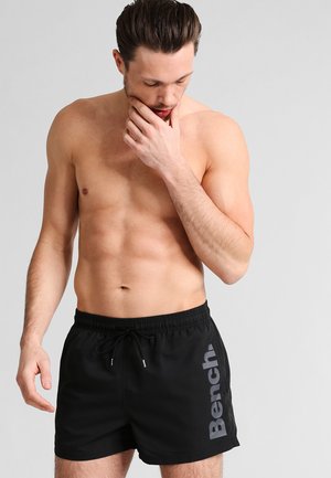 Schwarze Badehosen mit Kordelzugbund, ausgestattet mit einem großen grauen "Bench"-Logo auf der linken Seite. Glattes, leichtes Material.