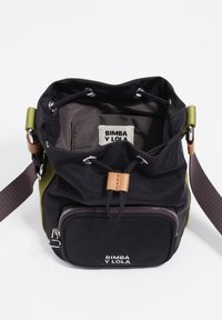 Czarna i oliwkowozielona torba typu bucket Bimba y Lola z zapięciem na ściągacz, przednią kieszenią na zamek oraz regulowanym paskiem na ramię na białym tle.