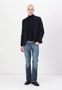 Black blazer, fitted black turtleneck, light blue straight-leg jeans, and black shoes. Smooth fabric with a structured design.