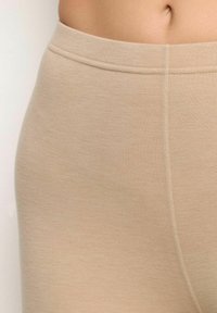 Leggings beige con una texture liscia e elastica. Presentano una cintura larga e cuciture piatte, progettati per comfort e flessibilità.