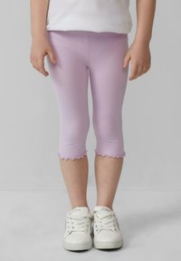 Lichtpaarse capri leggings met geschulpte zomen, gemaakt van rekbaar materiaal, gecombineerd met witte sneakers met gestikte details.