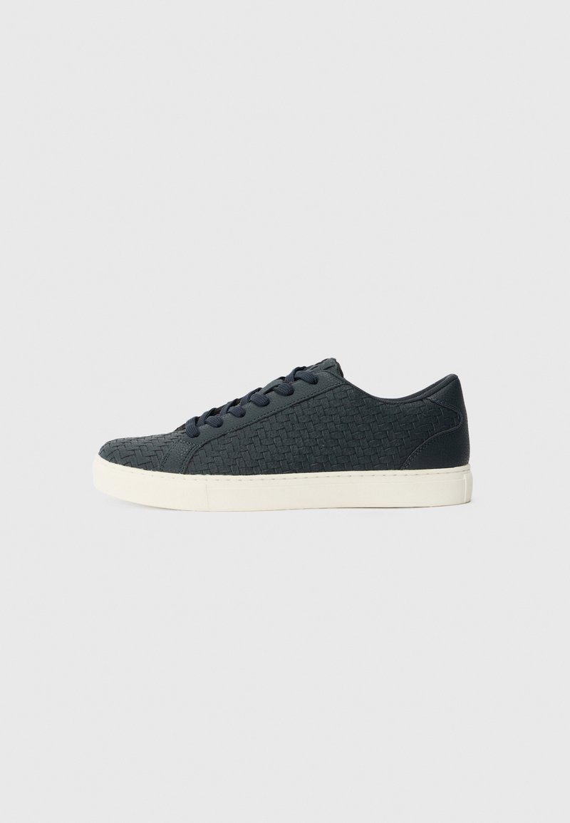 Baskets bleu foncé avec une texture tissée, bout rond, semelle en caoutchouc blanc et lacets assortis. Design minimaliste sans accents supplémentaires.
