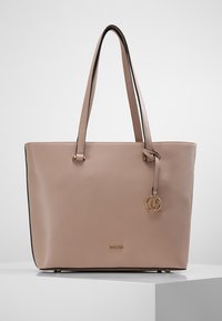 Beżowa torba na ramię ze skóry z dwoma uchwytami, czarną lamówką, złotym logo i zawieszką. Gładka tekstura o usztywnionym kształcie.