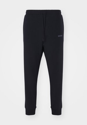 Pantalones de chándal negros fabricados en material suave, con cintura elástica, cordón ajustable y piernas ajustadas. Presenta un pequeño logo en el lateral.