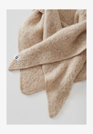 Beige wool blanket with a textured finish, featuring a stitched edge and a small tag in one corner. Soft and cozy appearance.