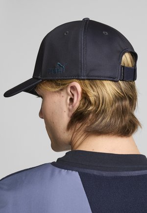 Cappellino sportivo blu navy in tessuto morbido, con visiera curva e fascia regolabile. Presenta il logo Puma ricamato in teal sulla parte anteriore.