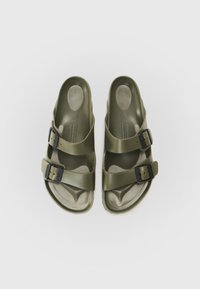 Sandales vert olive en plastique flexible avec deux boucles noires réglables et une semelle intérieure texturée pour une meilleure adhérence et un confort optimal.