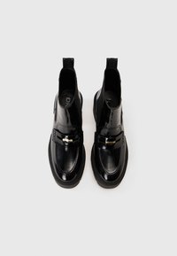 Botine scurte din piele lăcuită neagră, cu vârf rotund, laterale elastice și accente din metal aurit în față. Talpă largă, texturată.