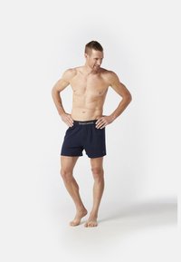 Tummansiniset boxerit, jotka on valmistettu pehmeästä materiaalista. Ne sisältävät joustavan vyötärönauhan, jossa on "Smartwool"-logo, ja ne istuvat rennosti.