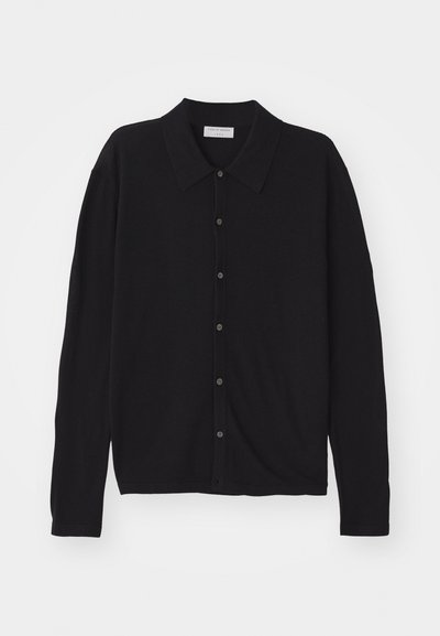 Crna kardigan jakna s ovratnikom, dugim rukavima i kopčanjem sprijeda. Izrađena od glatkog materijala s lagano ležernim krojem.