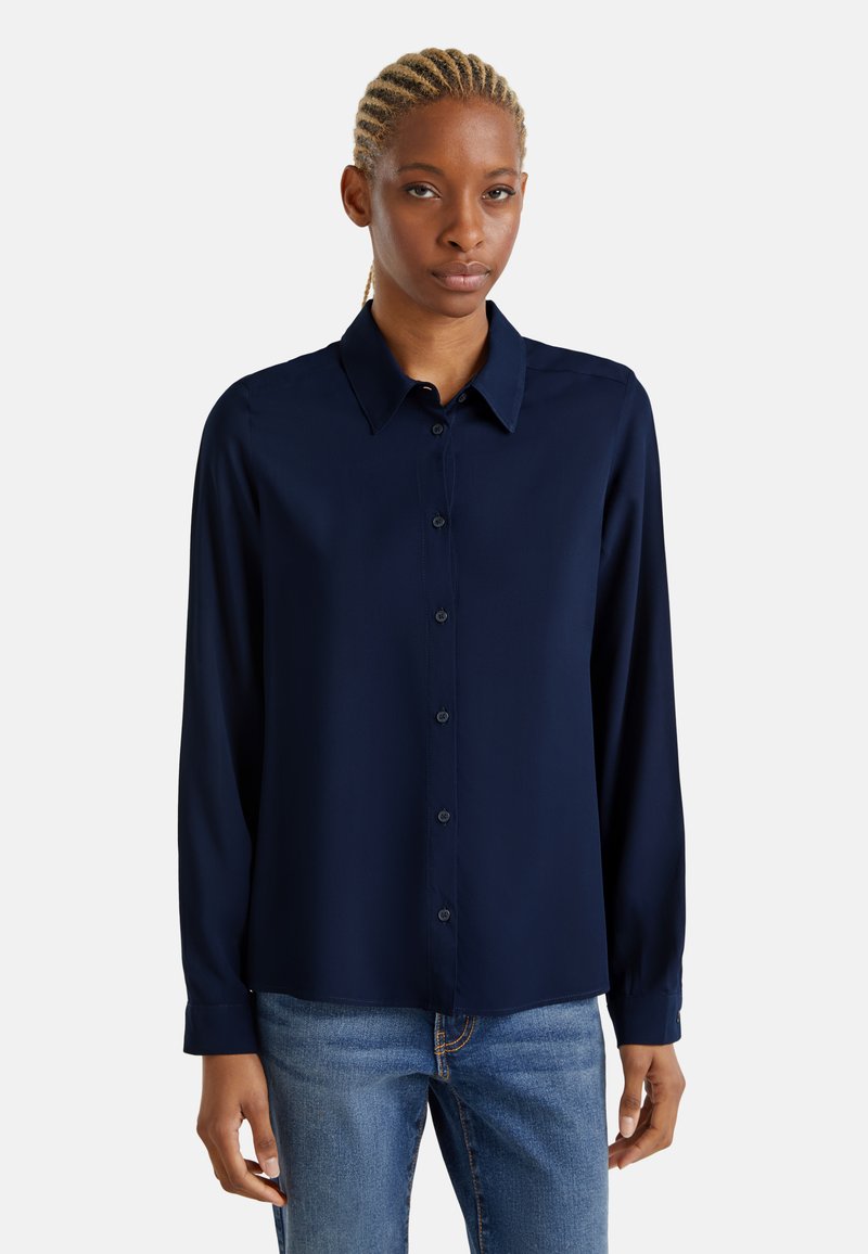 Camicia a maniche lunghe blu navy con colletto classico e taglio dritto, realizzata in un tessuto liscio, abbinata a jeans blu.