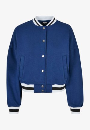 Chaqueta bomber azul con un cuello y puños acanalados a rayas blancas y negras. Incorpora botones a presión, bolsillos laterales y un diseño corto.