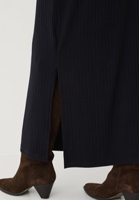 Marineblå, ribbet kjole med sideslids, der har en afslappet pasform og en glat tekstur. Sættet er kombineret med brune, suede hæle.