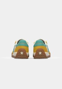 Sneakers with a yellow and teal suede upper, white accents, and a brown rubber outsole featuring a star detail.