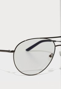 Óculos de sol com uma armação metálica fina preta, lentes redondas e almofadas para o nariz. As hastes apresentam destaques azuis. As lentes são ligeiramente tonais.