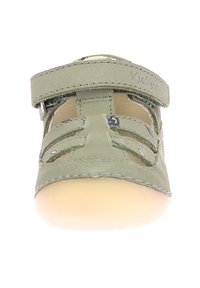 Zapato de cuero verde con diseño recortado, correa segura y suela de goma beige. Presenta un borde cosido y una marca en la correa.