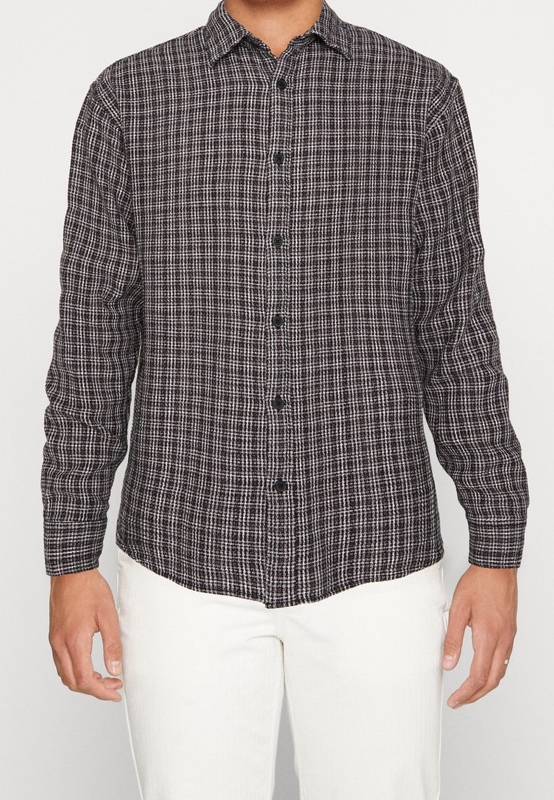 Schwarz-weiß kariertes Langarmhemd mit Knopfverschluss und halbtailliertem Schnitt aus strukturiertem Stoff.