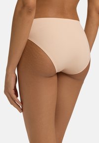 Hooggesneden bikini onderstuk in zacht beige stof. Heeft een gladde textuur, minimale bedekking en een schoon ontwerp zonder zichtbare naden.