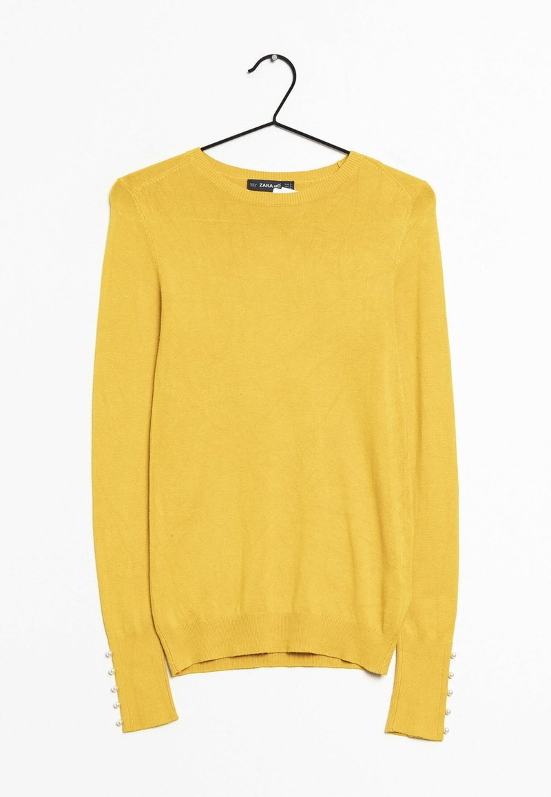 Pull en maille jaune avec des manches longues, un col rond, des fentes latérales et de petits boutons décoratifs blancs sur les poignets. Texture lisse.