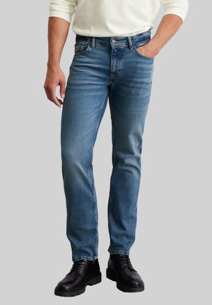 Blue denim jeans with a straight fit, stone-washed finish, five-pocket design, and top button, paired with black lace-up boots.
