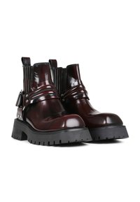 Bottes en cuir verni bourgogne avec des côtés élastiques, des accents de sangle, des finitions en métal argenté, des semelles en caoutchouc noir épaisses et des motifs de traction robustes.