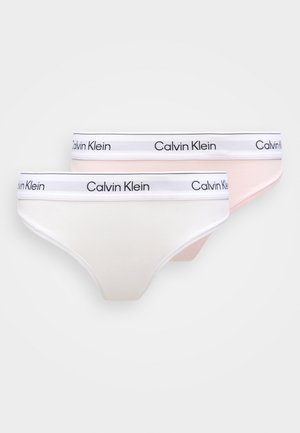 Dvi Calvin Klein stringų kelnaičių poros; viena balta ir viena šviesiai rožinė, pasižyminčios minkšta medžiaga ir elastine juosmens juosta su logotipu.