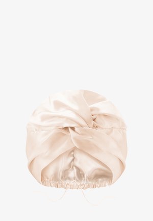 Zijdeachtig beige tulbandstijl hoofdband met een gedraaid knoopontwerp en een elastische band aan de achterkant voor een veilige pasvorm.