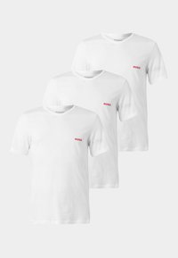 Trois t-shirts blancs à manches courtes avec col en V et petit logo rouge "HUGO" sur la poitrine gauche, affichés en disposition décalée.