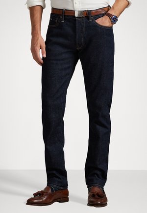 Mørkeblå denim jeans med lige pasform, der har et brunt læderbælte, klassisk fem-lomme design og kontraststikningsdetaljer.