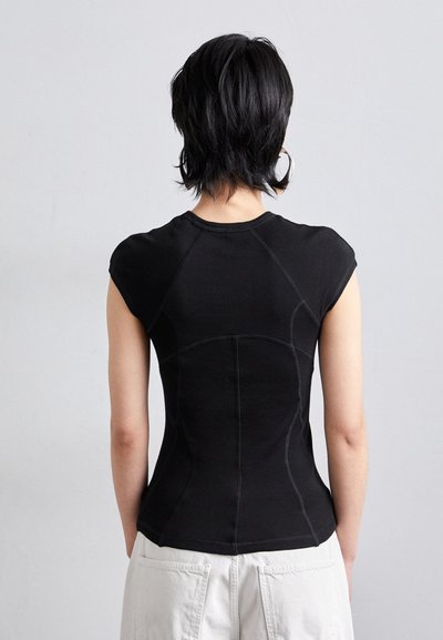 Top noir ajusté avec de courtes manches en cap, présentant des détails de couture contrastés et une texture lisse. Conçu avec une forme courbée et contournée.