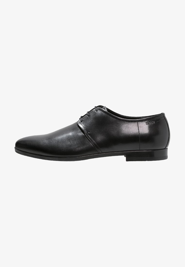 Zapato de vestir para hombre de piel negra pulida, con punta puntiaguda, cierre de cordones y tacón bajo, mostrado desde el lado exterior.