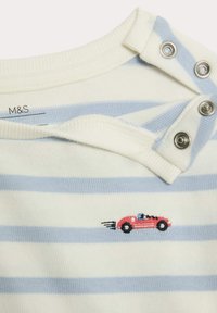 Randig skjorta i kräm och ljusblå, med en röd broderad bild av en bil. Inkluderar silverknappar med tryck på axeln.