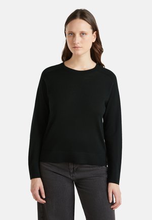 Zwarte trui van zacht materiaal, met een ronde hals, lange mouwen en een relaxte pasvorm. Gewelfde accenten op de schouders.