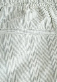 Tissu rayé aux tons crème clair et gris subtil, doté d'une ceinture élastique et d'une poche arrière avec couture simple.