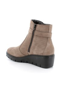Stivale alla caviglia in suede marrone con zip laterale, suola in gomma nera spessa e tacco basso a zeppa. Texture liscia con cuciture minime.