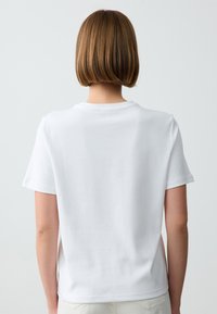 Witte T-shirt met korte mouwen, ronde hals, gladde katoenen stof, relaxte pasvorm, eenvoudig ontwerp zonder zichtbare logo's of patronen.