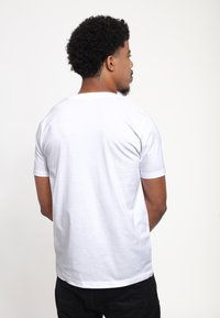 White cotton t-shirt with short sleeves, crew neck, and a smooth texture. Simple design, no patterns or accents visible.