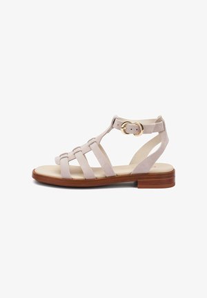 Beige suède platte sandaal met houten zool, meerdere bandjes, enkelbandje en gouden dubbele gespsluiting.