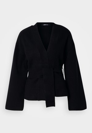 Cardigan negru din material tricotat, care prezintă un decolteu în V, mâneci largi și o curea asortată la talie. Textură netedă.